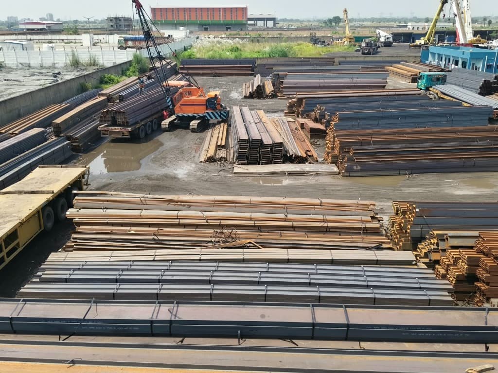 Aerial stockyard view with heavy crane operations and steel inventory